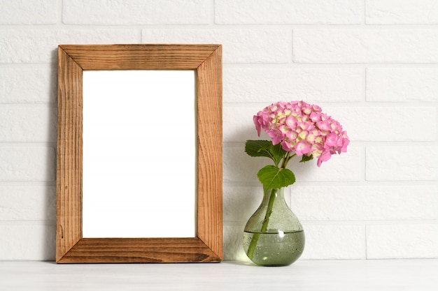 Empty wooden frame and flower in glass vase