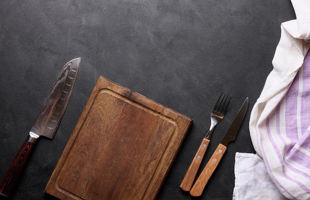 Empty wooden kitchen cutting board knife and fork with wooden handle on black background top view