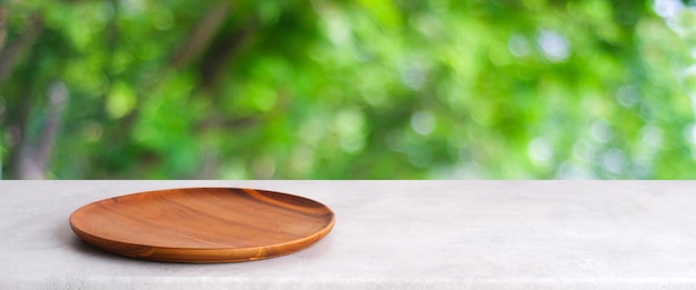 Empty wooden plate on white table over blur green trees nature with bokeh background