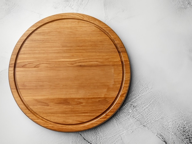 Empty wooden round board on white stone kitchen table top view flat lay Wooden pizza platter cop