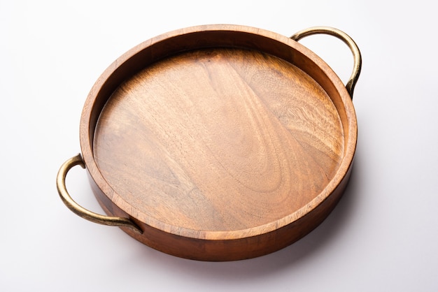 Empty wooden round tray with brass handle on white surface