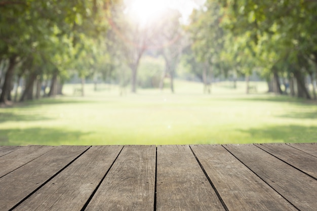 Empty wooden table / floor in public park blur background with green trees