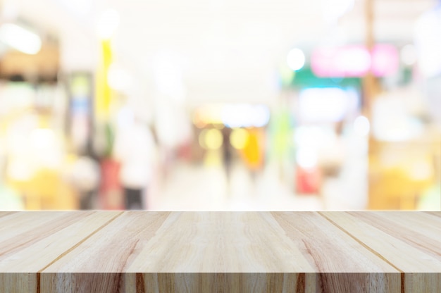 Empty wooden table top with blurred modern shopping mall background. 