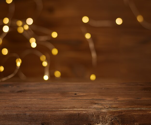 Empty wooden table with Christmas lights in the background