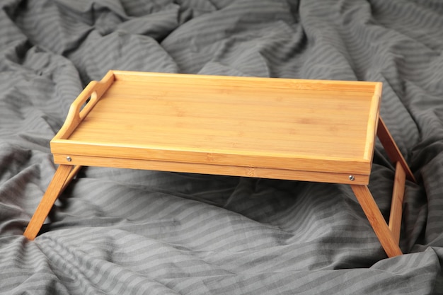 Empty wooden tray on a grey bed