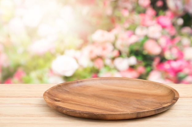 Empty wooden tray on perspective wooden table on top over blur flower background