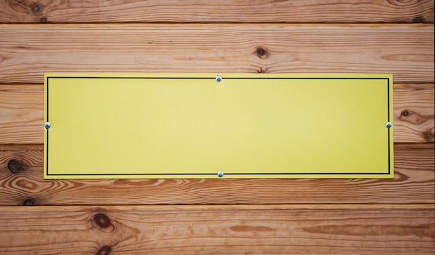 Empty yellow nameplate on wooden board