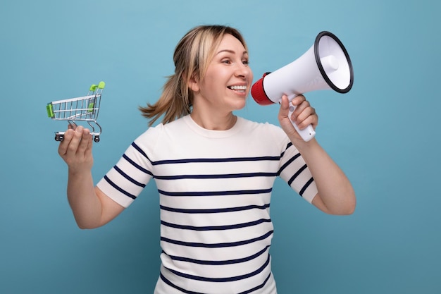 Energetic blond attractive young woman in casual outfit announces sale using loudspeaker holding