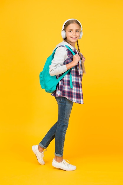 Energetic cheerful teen listening music Stylish schoolgirl going to school Girl little fashionable girl with backpack School life Happy carefree child School classes Student Modern education