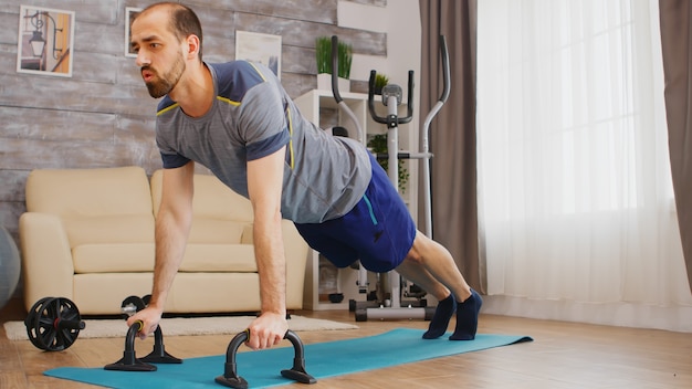 Energetic man doing chest workout on yoga mat at home.