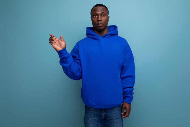 Photo energetic positive young african man consultant in stylish hoodie shows with hand actual offer on