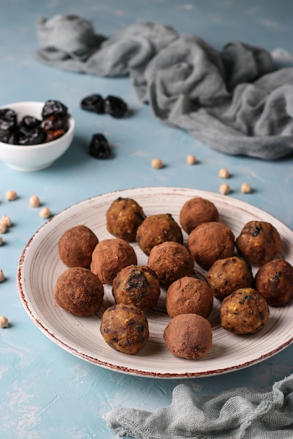 Energy balls of chickpea, prunes and dates, sprinkled with cocoa on a light blue background