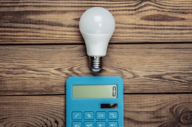 Energy saving concept. Calculator with light bulb on a wooden