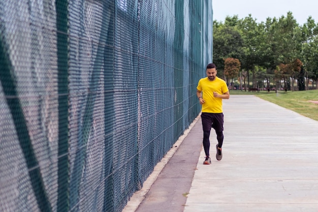 Engaged in activities to improve health and body a bearded man in a tracksuit runs along a road