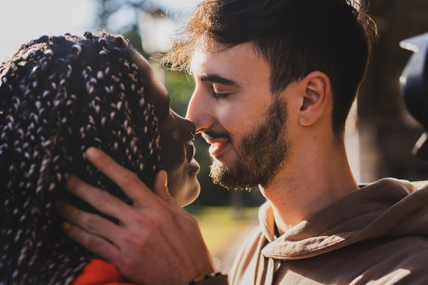 Engaged biracial couple of generation z young people kissing in the park - closeup shot