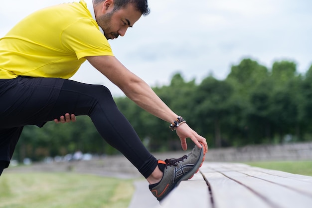 Engaged in a springtime workout at an urban park a flexible man in black leggings trains his leg