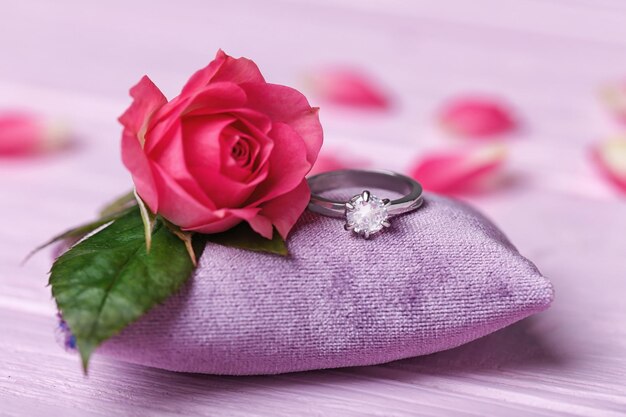 Engagement ring and beautiful rose on small pillow closeup