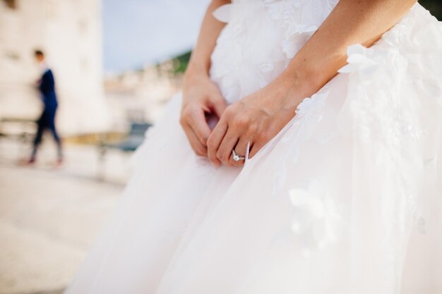 Engagement ring on brides hand with wedding dress close up