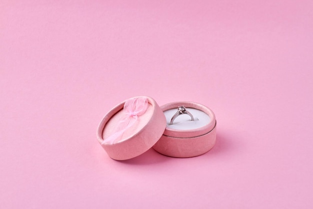 Engagement ring in pink gift box on pink background