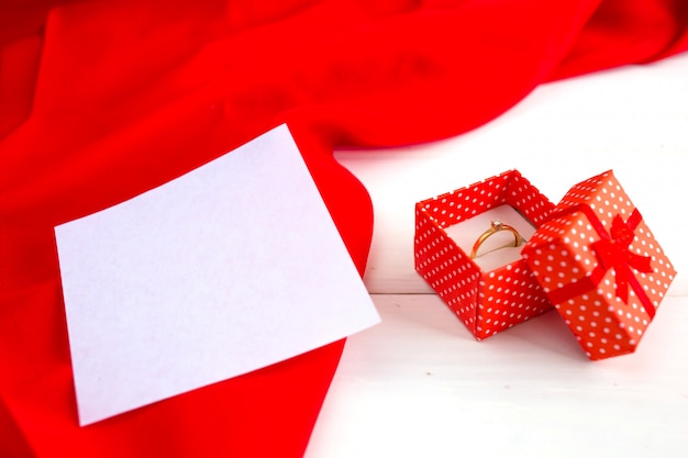 Engagement ring in a red box on a white wooden background. Declaration of love on Valentine's Day