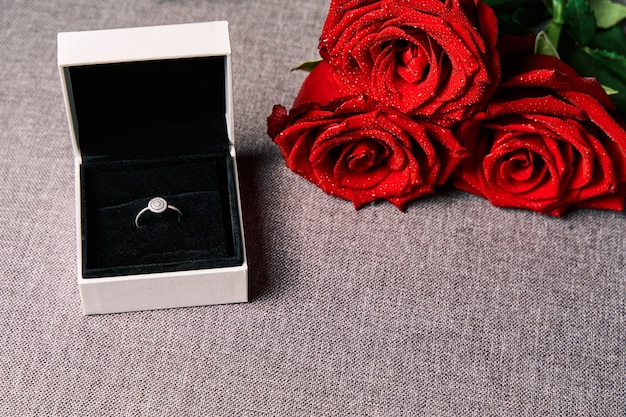 Engagement ring and red roses as a gift. Concept of Valentine's Day and marriage.