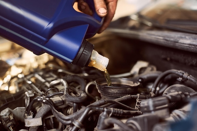 Engine oil changing and maintenance gear car engine in auto service workshop Close up of pouring motor oil into engine