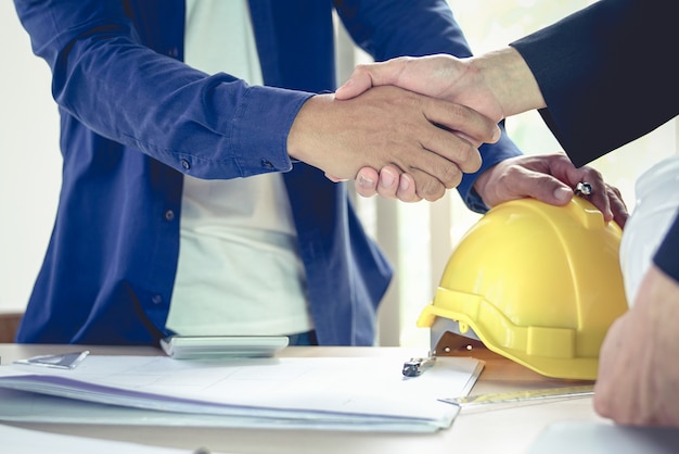 Engineer and architect shake hands agree deal of construction plans