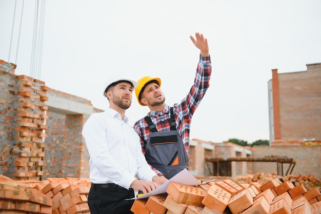 Engineer architect with hard hat and safety vest working together in team on major construction site