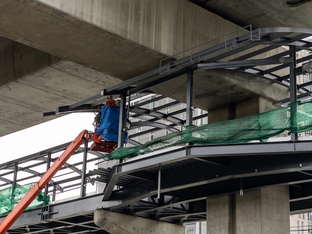 The engineer in the bucket of the crane vehicle for checking the metal frame