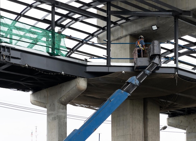 The engineer in the bucket of the crane vehicle for checking the metal frame