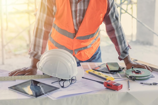 Engineer builder desk working space in construction site with floor plan or blueprint of building