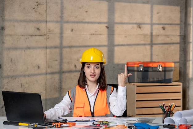 Engineer cute young smart brunette girl civil worker in helmet and vest having an idea