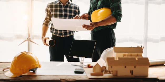 Engineer desk with object paper and tablet with blurry engineer teamwork hardworking to consults about their building project