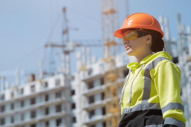 An engineer in a green hoodie with reflective ribbons and a construction control helmet