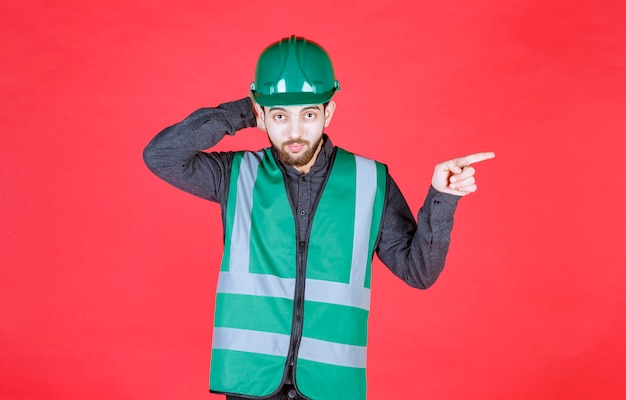 Engineer in green uniform and helmet showing the right side. 