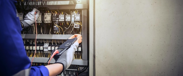 Engineer hand holding AC voltmeter checking electric current voltage at circuit breaker terminal