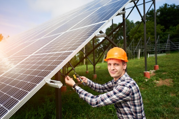 Engineer in helmet connects solar panels on a green plantation Green ecological power energy generation