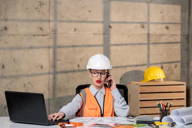 Engineer in helmet and vest civil worker smart young cute blonde girl on phone call