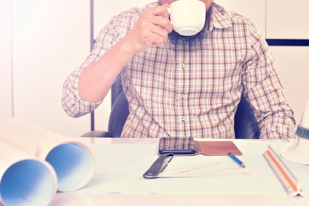 Engineer is working on the desk with drawing plan