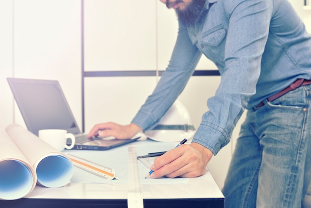 Engineer is working on the desk with drawing plan