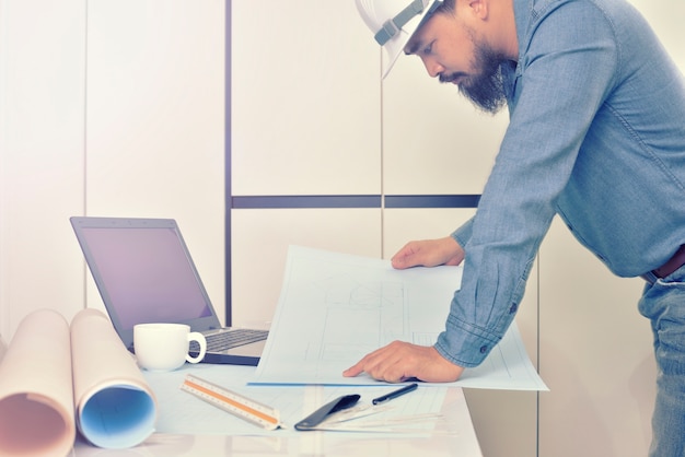 Engineer is working on the desk with drawing plan