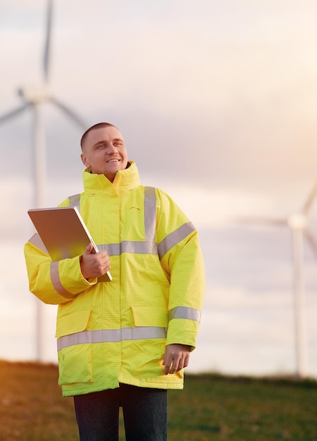 Engineer man stands in a wind turbine field