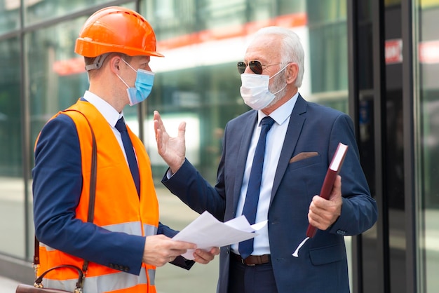 Engineer man with mask discussing something with senior business man with mask