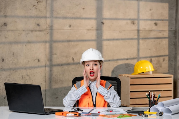 Engineer smart young cute blonde girl civil worker in helmet and vest yelling