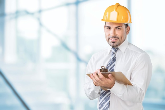 Engineer taking a note. Focused man in white hardhat holding a clipboard and writing.