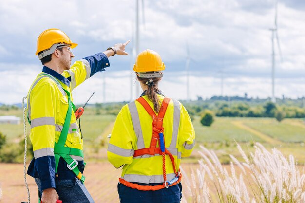 Photo engineer team working group survey at wind turbine clean power generator service maintenance wind mill outdoor