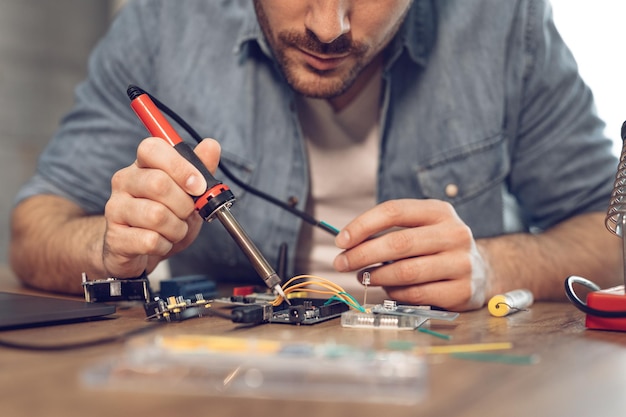 Photo engineer or technician focused on repair electronic circuit board with soldering iron.