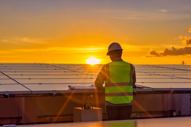 engineer using laptop at solar panels on rooftop at sunset sky  engineer working at a photovoltaic