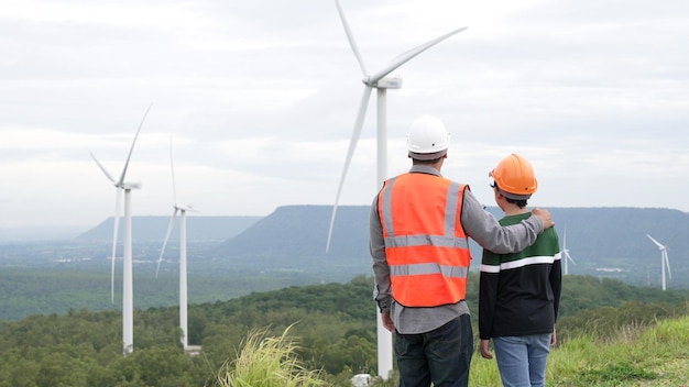 Engineer with his son on a wind farm atop a hill or mountain in the rural Progressive ideal for the future production of renewable sustainable energy Energy generation from wind turbine