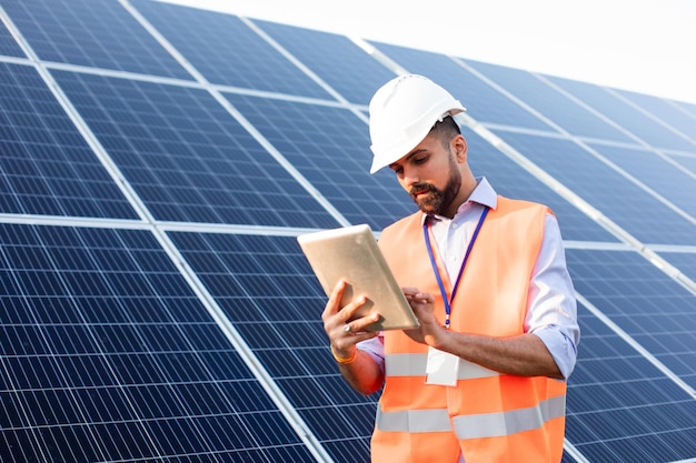 Engineer with a tablet stands on the background of a solar station